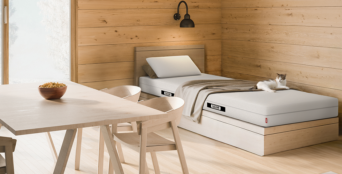 Foto: Eine Matratze in einem spartanisch eingerichteten Raum aus Holz.